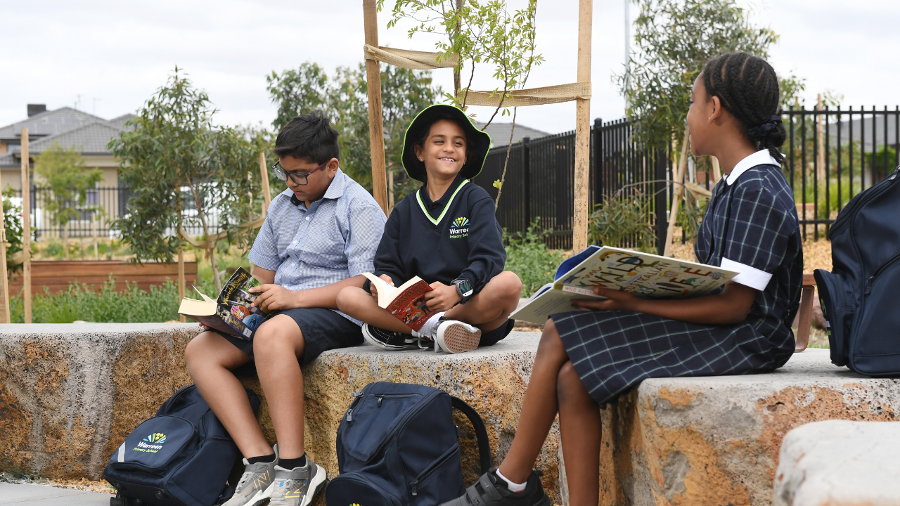 Three students sitting outside reading at school