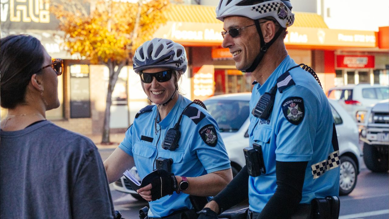Female and male police officers talking to a woman on a street